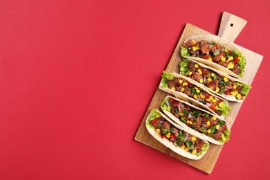 Photo of Delicious tacos with meat and vegetables on red table, top view. Space for text