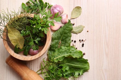 Photo of Mortar with pestle and different ingredients on wooden table, flat lay. Space for text