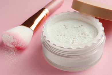 Rice loose face powder and makeup brush on pink background, closeup