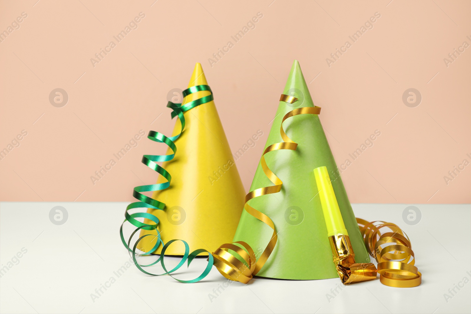 Photo of Colorful party hats, streamers and blower on white table. Birthday celebration