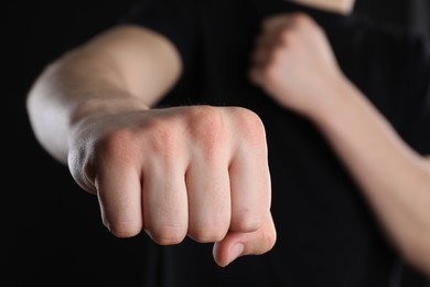 Man showing fist with space for tattoo on black background, selective focus