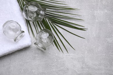 Glass cups, green leaf and towel on grey table, flat lay with space for text. Cupping therapy