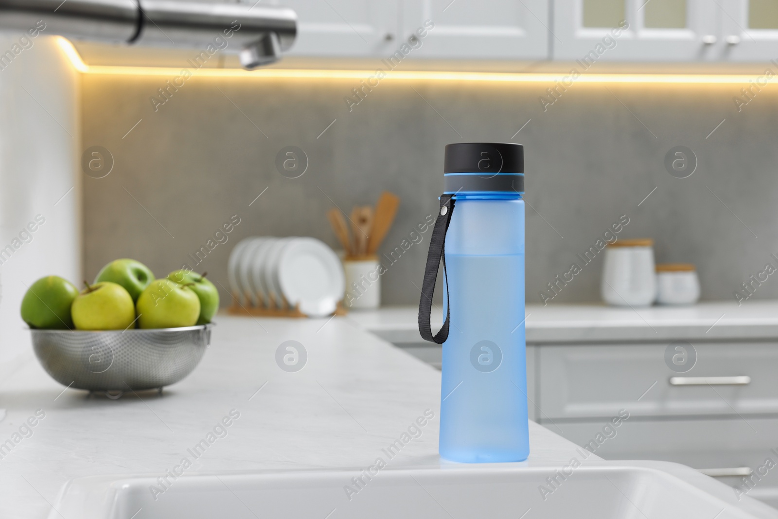 Photo of Stylish thermo bottle on white countertop in kitchen. Space for text