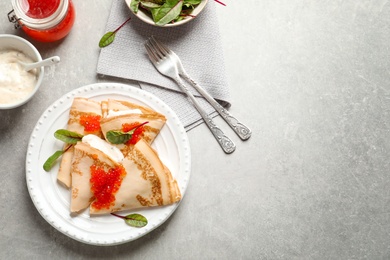 Thin pancakes served with red caviar on plate, top view