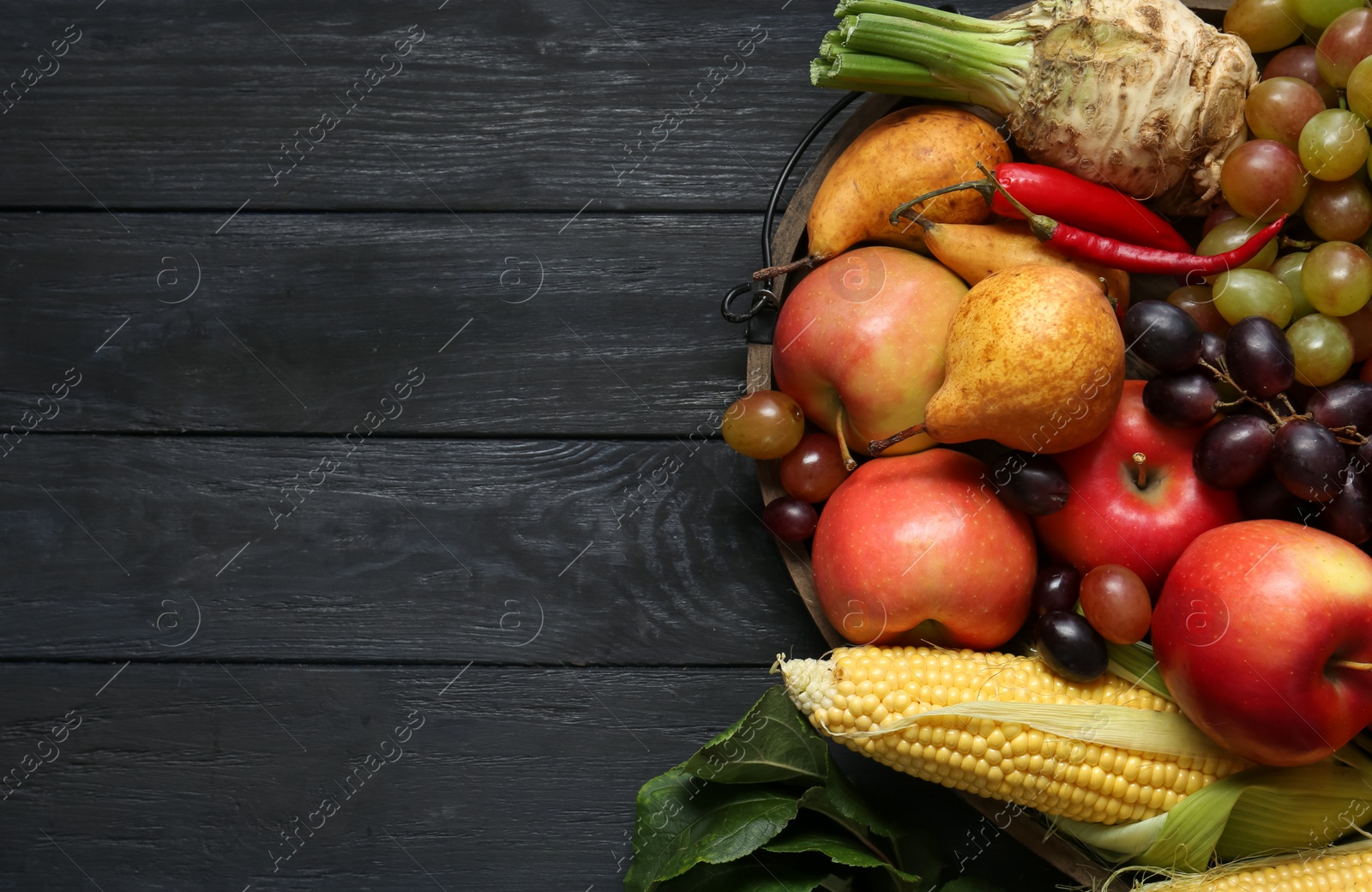 Photo of Different fresh vegetables and fruits on black wooden table, top view with space for text. Farmer harvesting