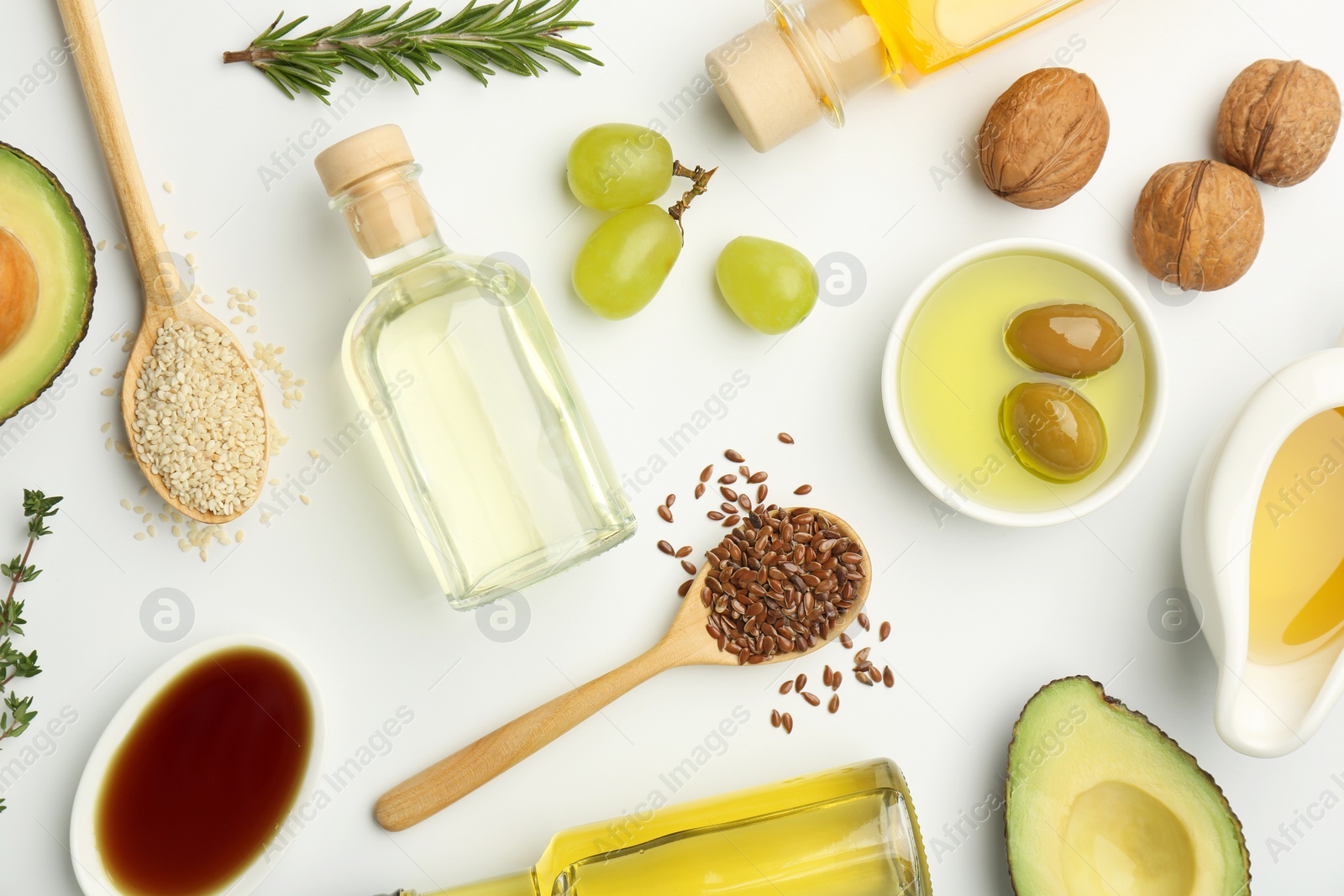 Photo of Vegetable fats. Different oils in glass bottles and ingredients on white table, flat lay