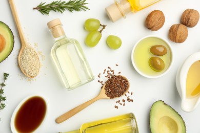 Vegetable fats. Different oils in glass bottles and ingredients on white table, flat lay