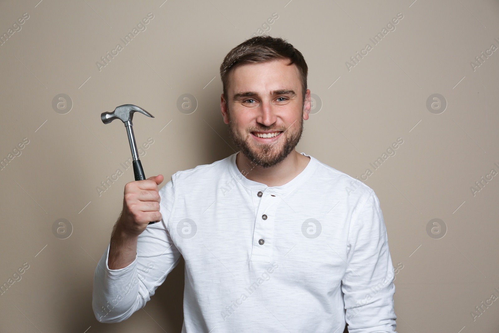 Photo of Young working man with hammer on beige background