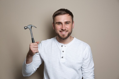 Photo of Young working man with hammer on beige background