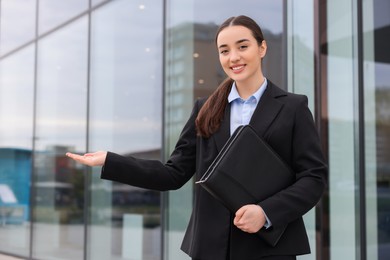 Photo of Female real estate agent with leather portfolio outdoors