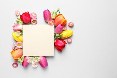 Photo of Beautiful composition with spring flowers and blank card on white background, top view. Space for text