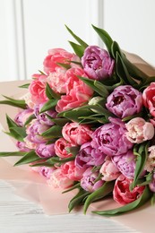 Photo of Bouquet of beautiful tulips on white wooden table, closeup