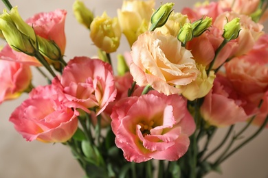 Photo of Beautiful Eustoma flowers against beige background, closeup