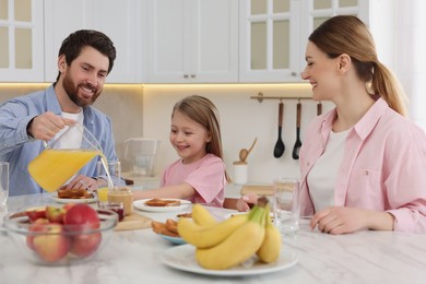 Photo of Happy family having breakfast at table in kitchen