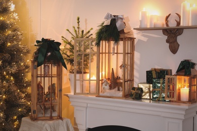 Beautiful wooden lanterns and other decorations on mantelpiece in room with Christmas tree