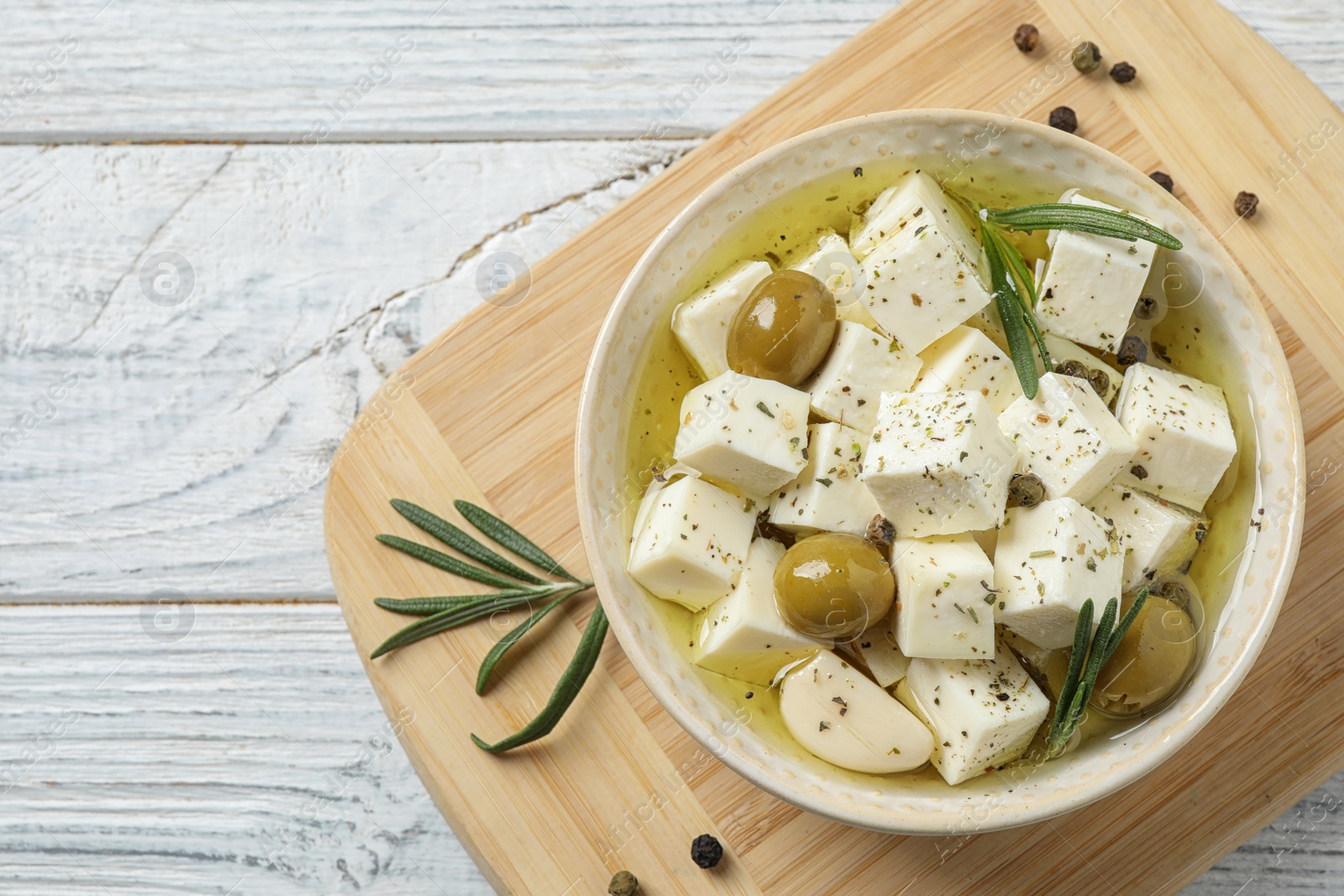 Photo of Flat lay composition with pickled feta cheese in bowl on white wooden table