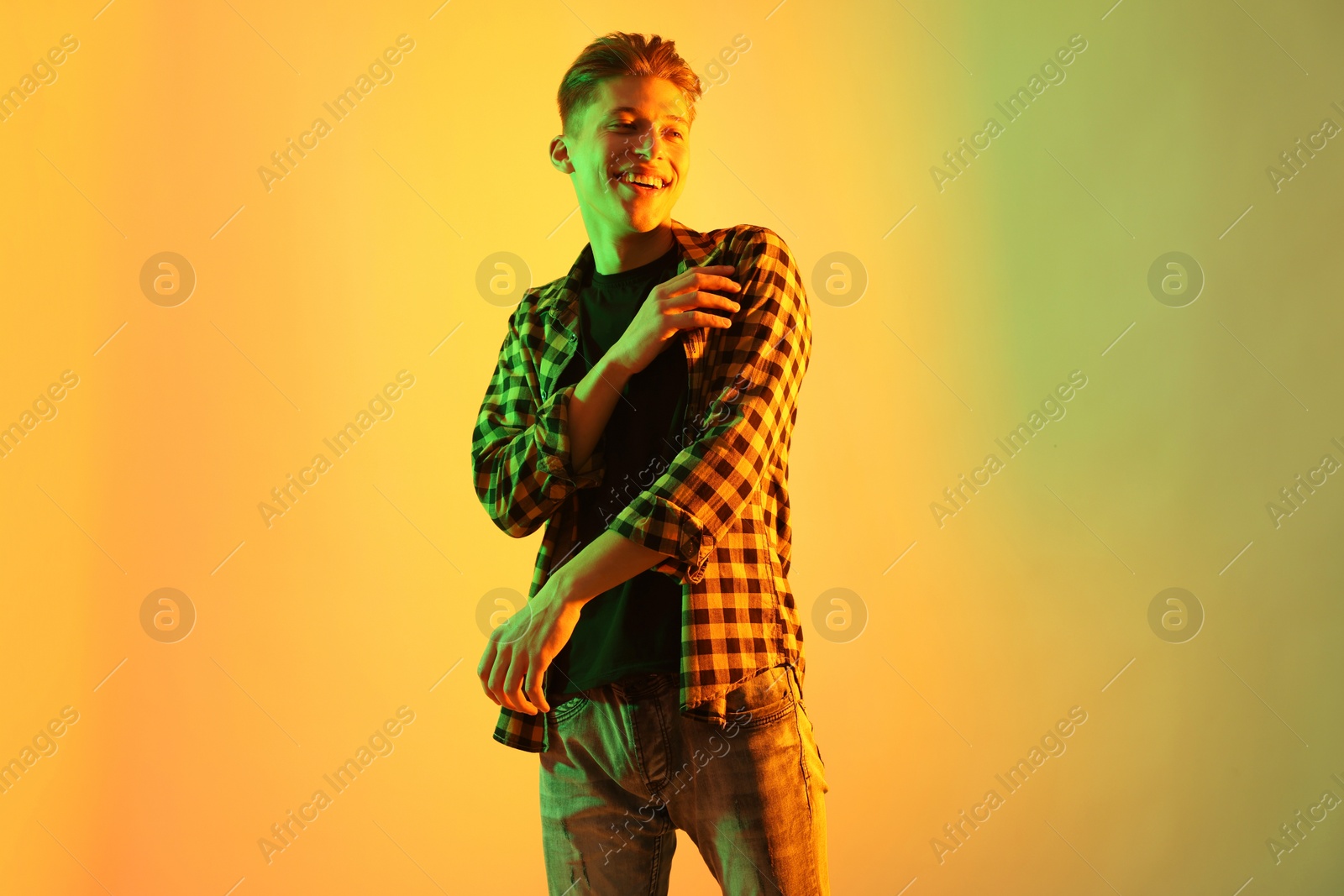 Photo of Young man dancing on color background in neon lights