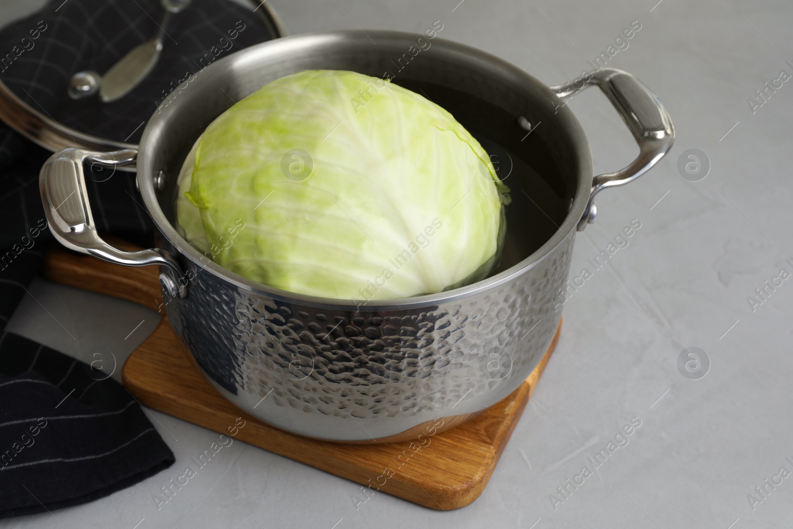 Photo of Sauce pan with hot water and cabbage for preparing stuffed rolls on light grey table