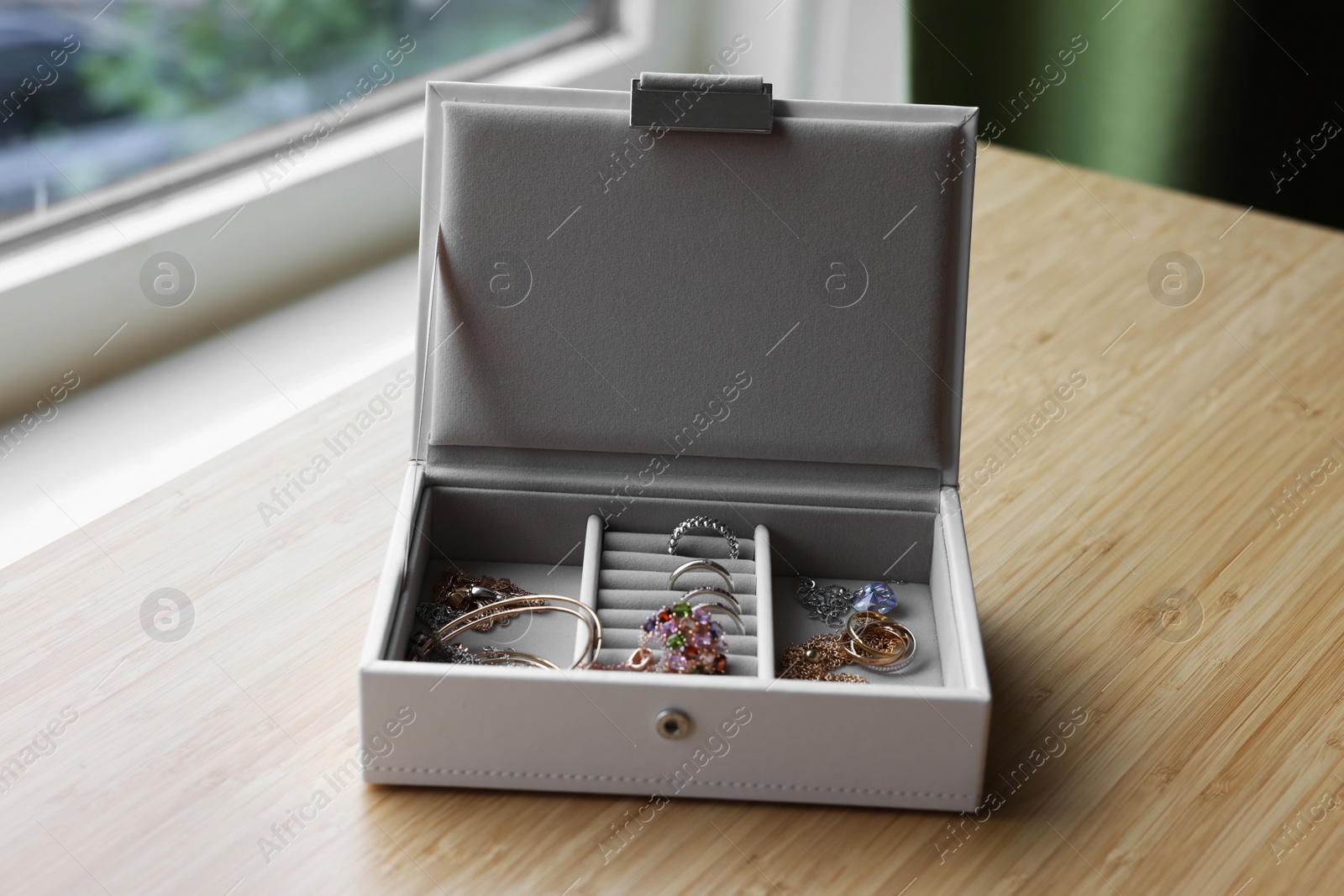 Photo of Jewelry box with many different accessories on wooden table