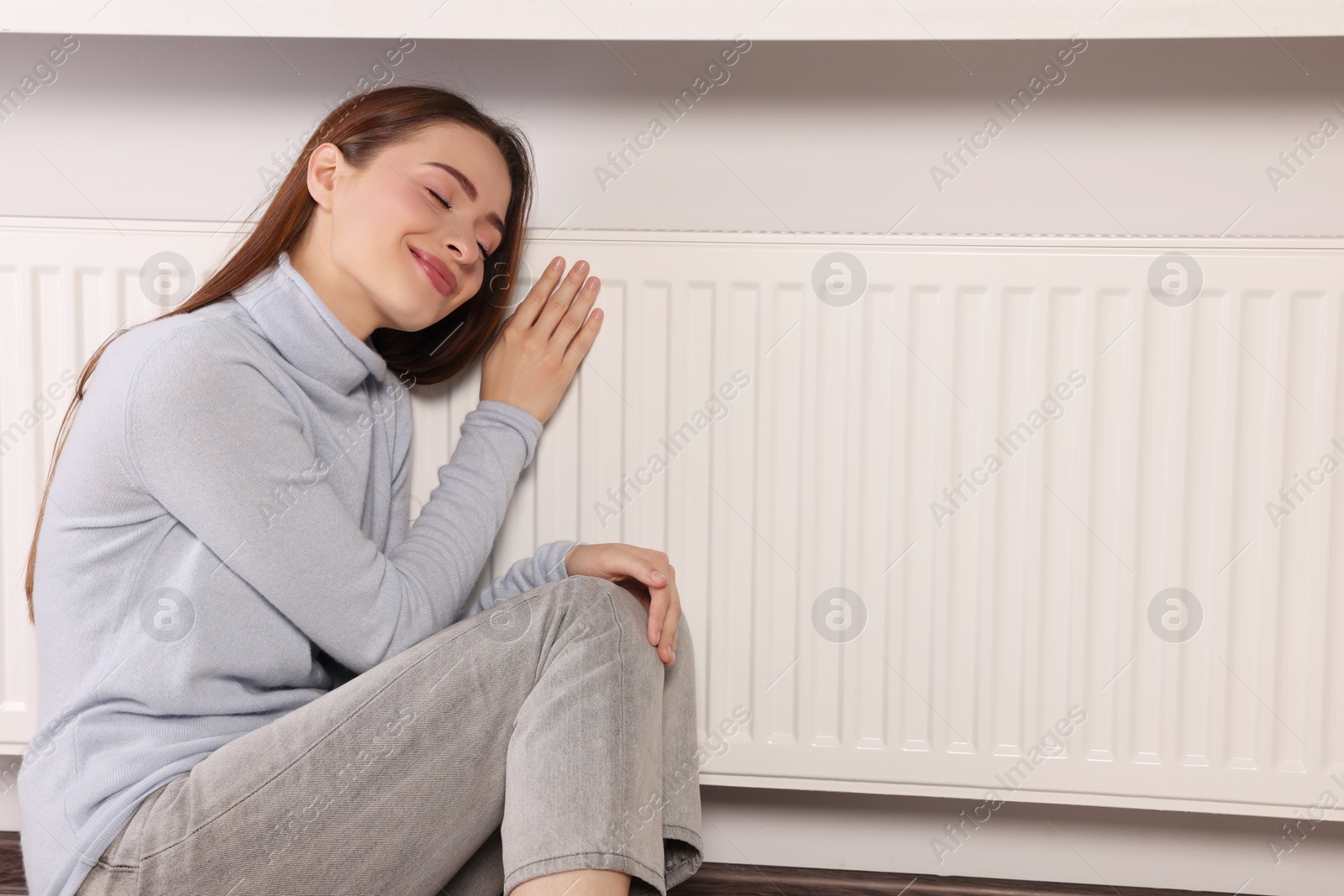 Photo of Woman near heating radiator indoors, space for text