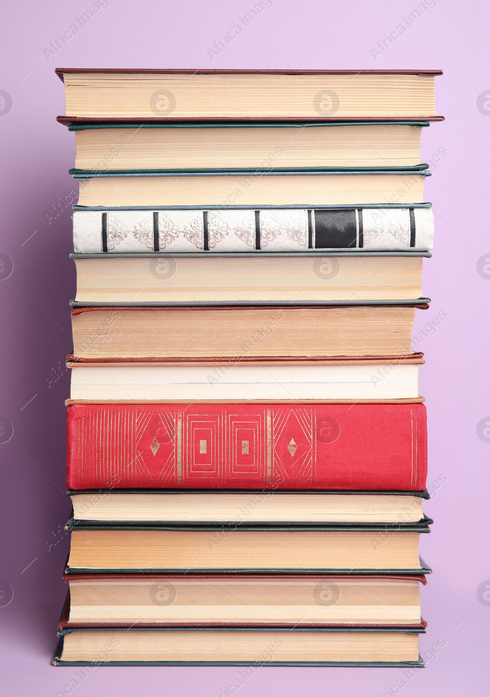 Photo of Stack of different hardcover books on violet background