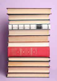 Stack of different hardcover books on violet background