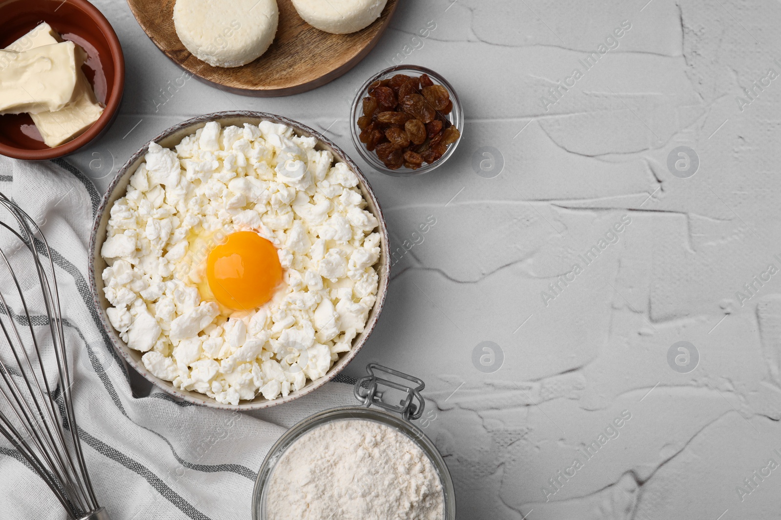 Photo of Different ingredients on white textured table, flat lay and space for text. Cooking cottage cheese pancakes