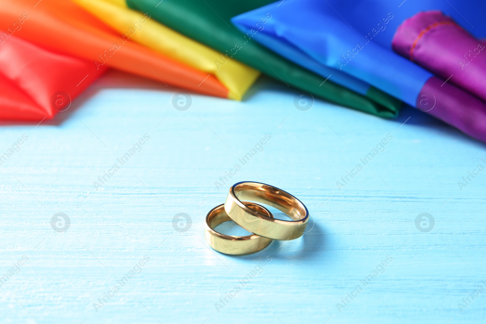 Photo of Wedding rings and rainbow flag on wooden table. Gay marriage