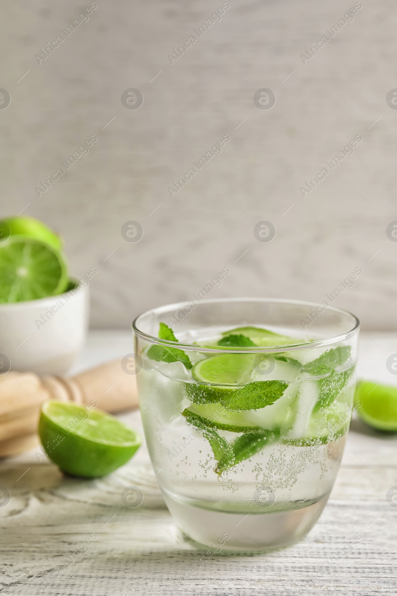 Photo of Refreshing beverage with mint and lime in glass on table