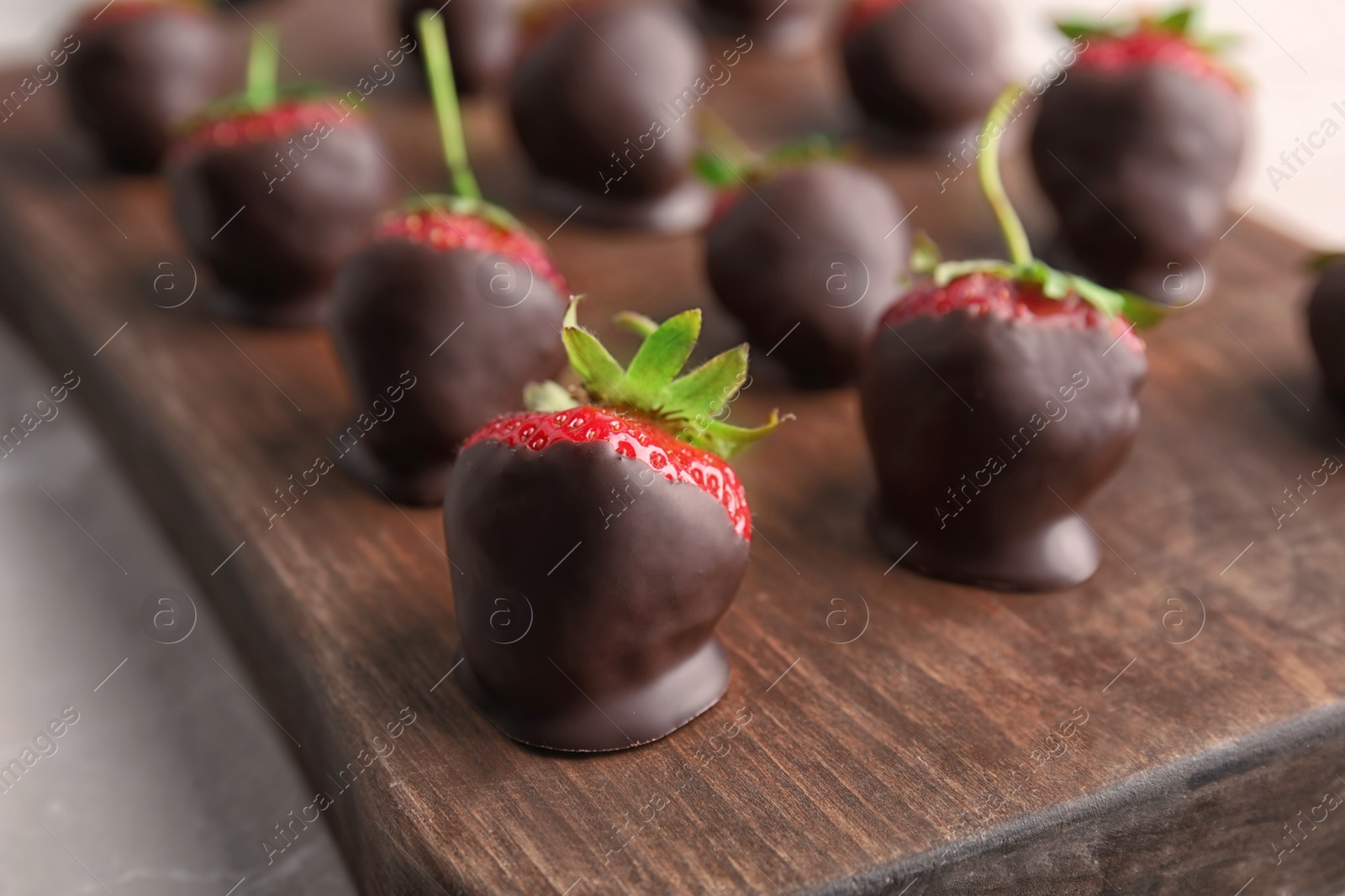 Photo of Chocolate covered strawberries on wooden board, closeup