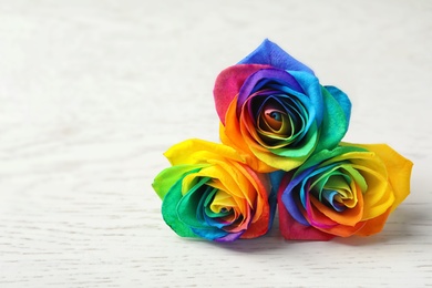 Photo of Amazing rainbow rose flowers on table