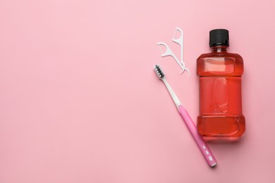 Photo of Mouthwash, toothbrush and dental floss on pink background, flat lay. Space for text