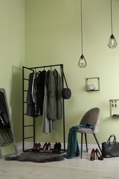 Modern dressing room interior with clothing rack, chair and mirror