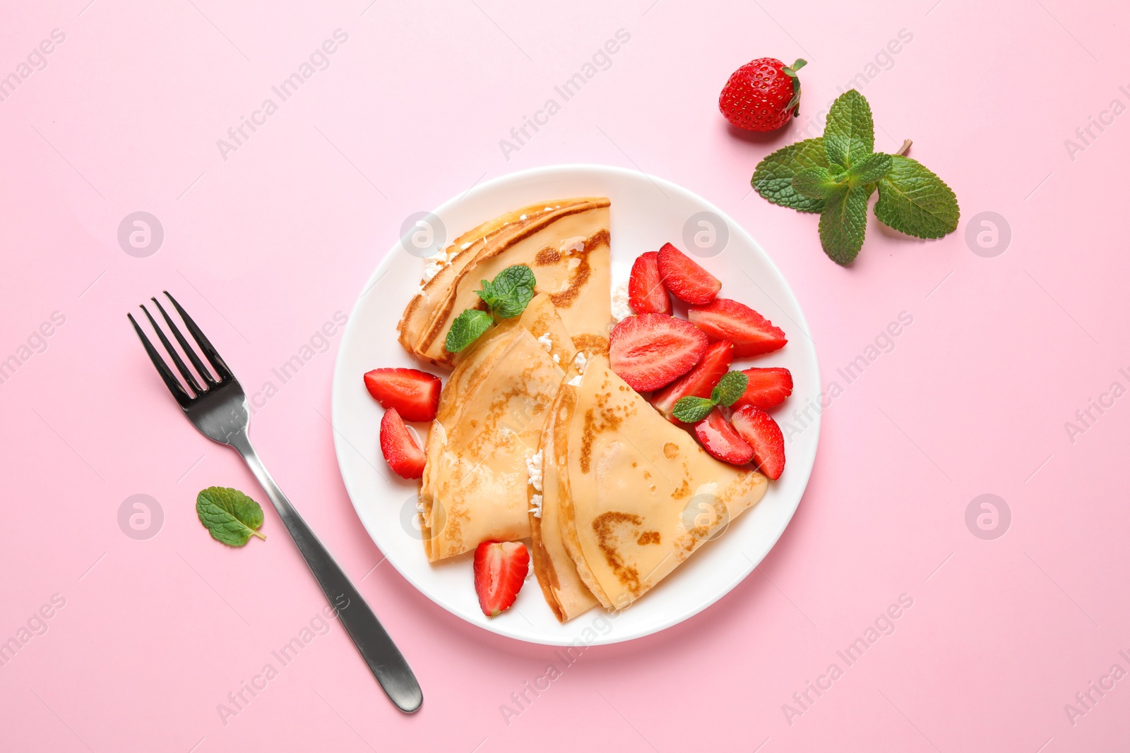 Photo of Delicious thin pancakes with strawberries and cottage cheese on pink background, flat lay