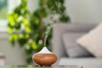 Photo of Aroma oil diffuser lamp on table against blurred background