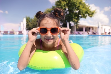 Photo of Little girl with inflatable ring in swimming pool