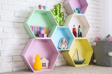 Colorful shelves near brick wall in child room interior