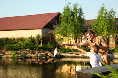 Photo of Dad and son fishing together on sunny day