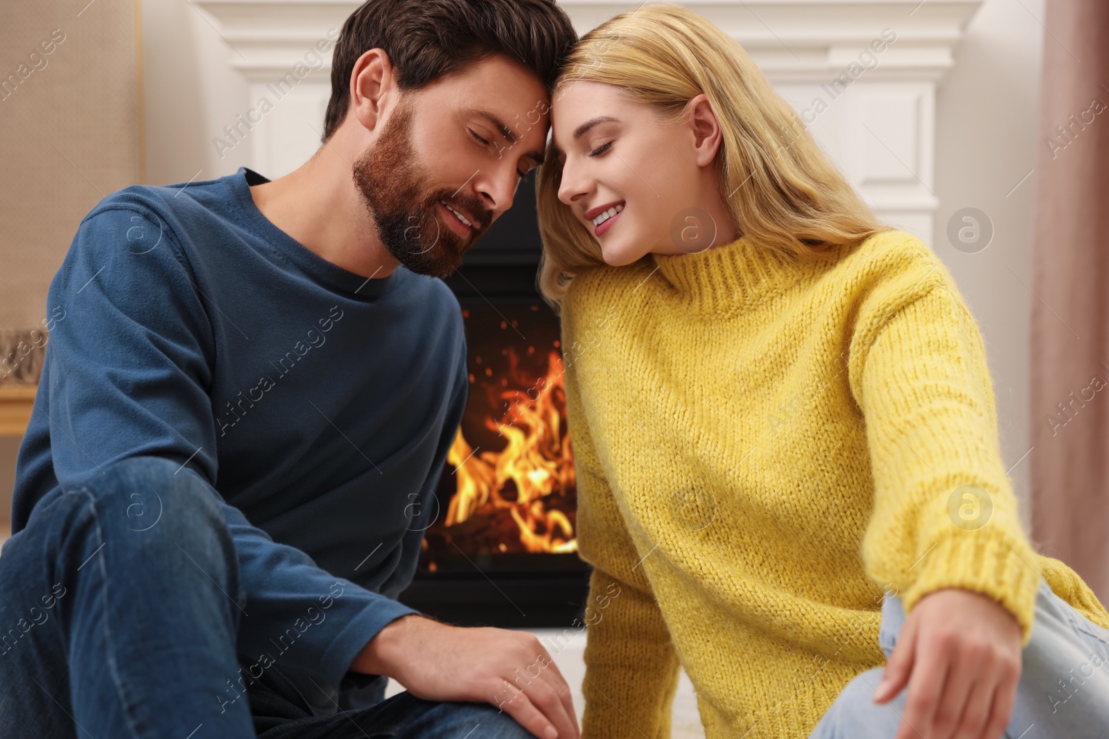 Photo of Lovely couple spending time together near fireplace indoors