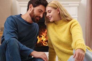 Lovely couple spending time together near fireplace indoors