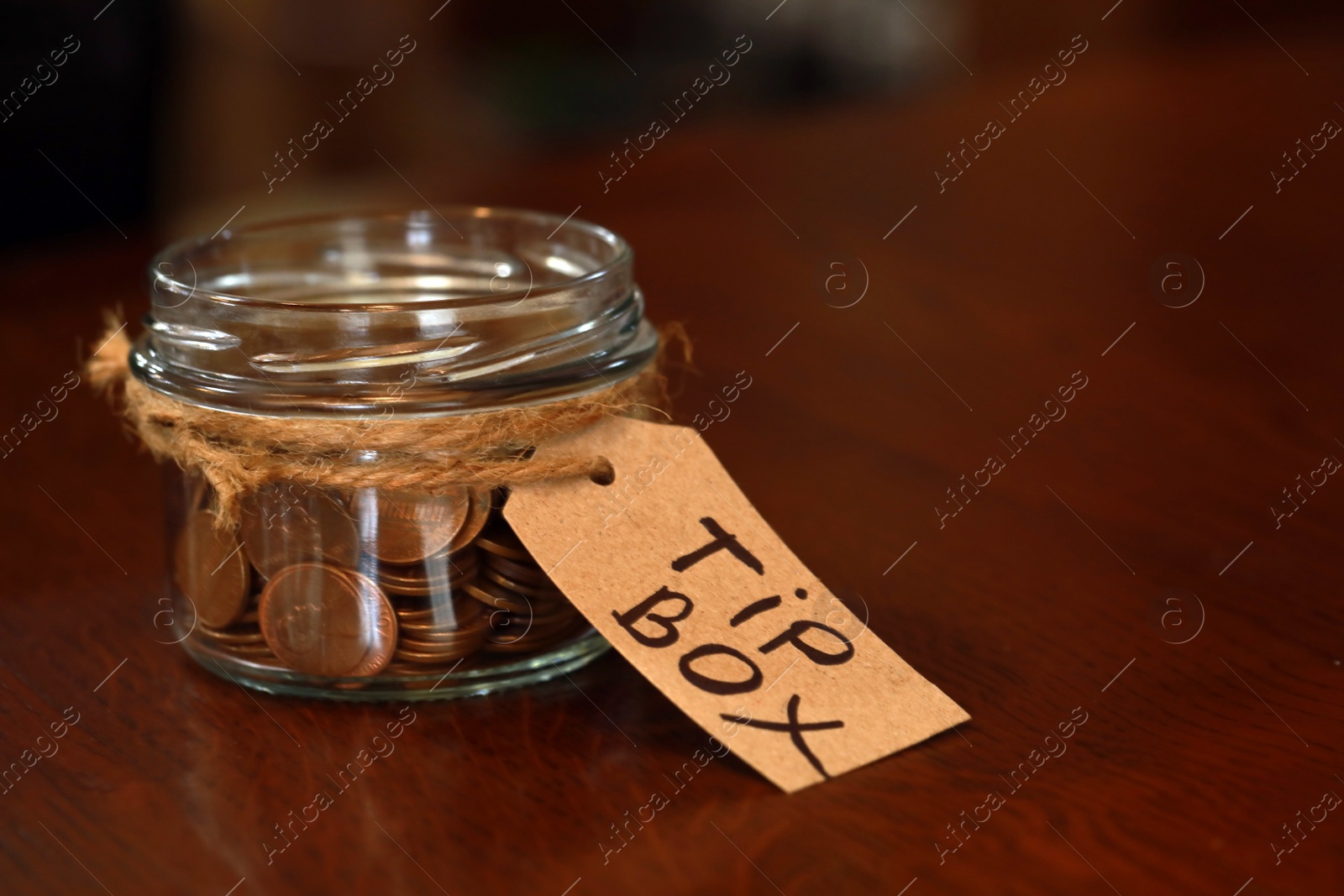 Photo of Tip box full of coins on wooden table in cafe, space for text