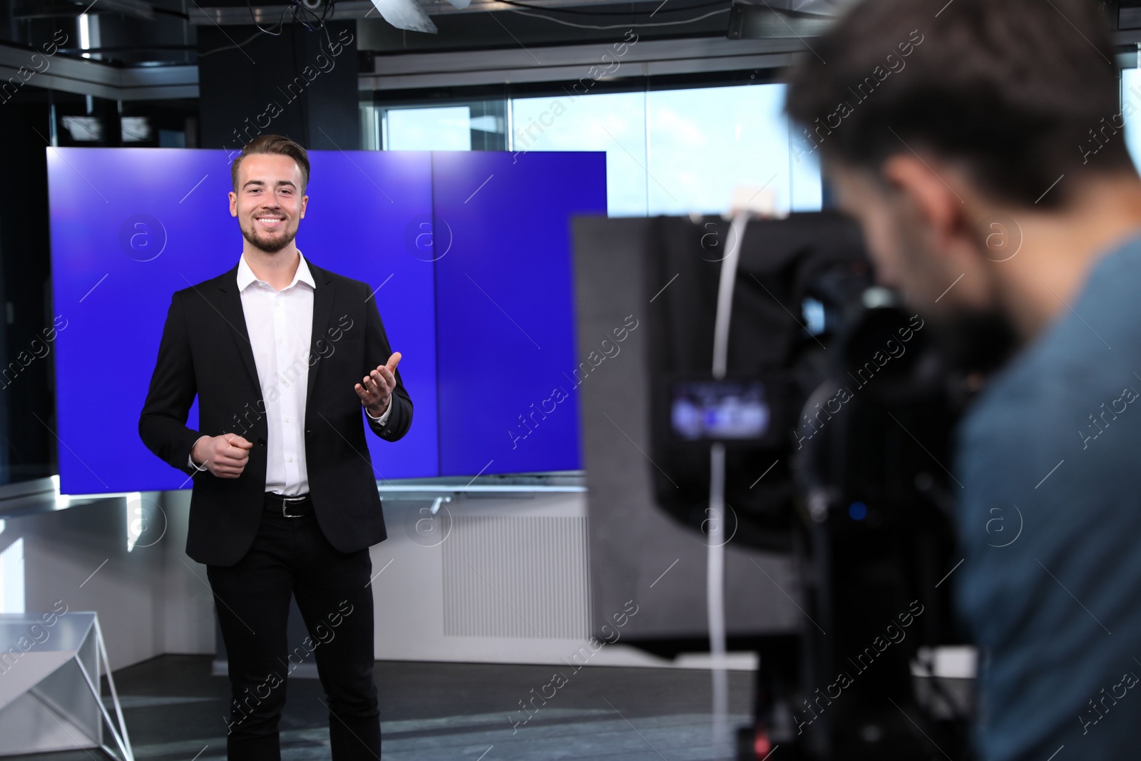 Photo of Presenter and video camera operator working in studio. News broadcasting