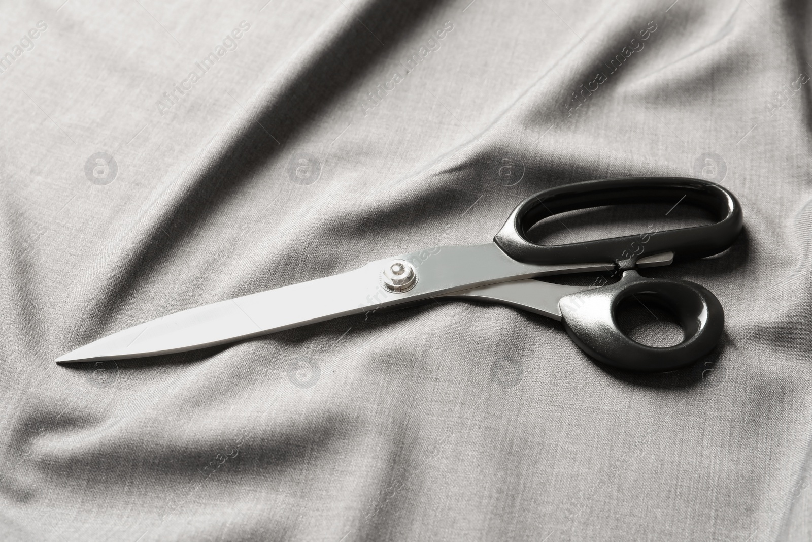 Photo of Scissors on soft grey fabric. Tailoring equipment