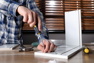 Photo of Man assembling furniture at table indoors, closeup