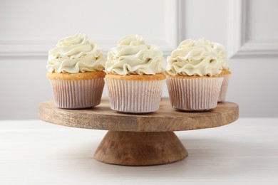 Photo of Tasty vanilla cupcakes with cream on white wooden table