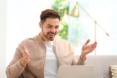 Photo of Man using laptop for video chat in living room