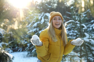 Woman holding snowballs outdoors on winter day