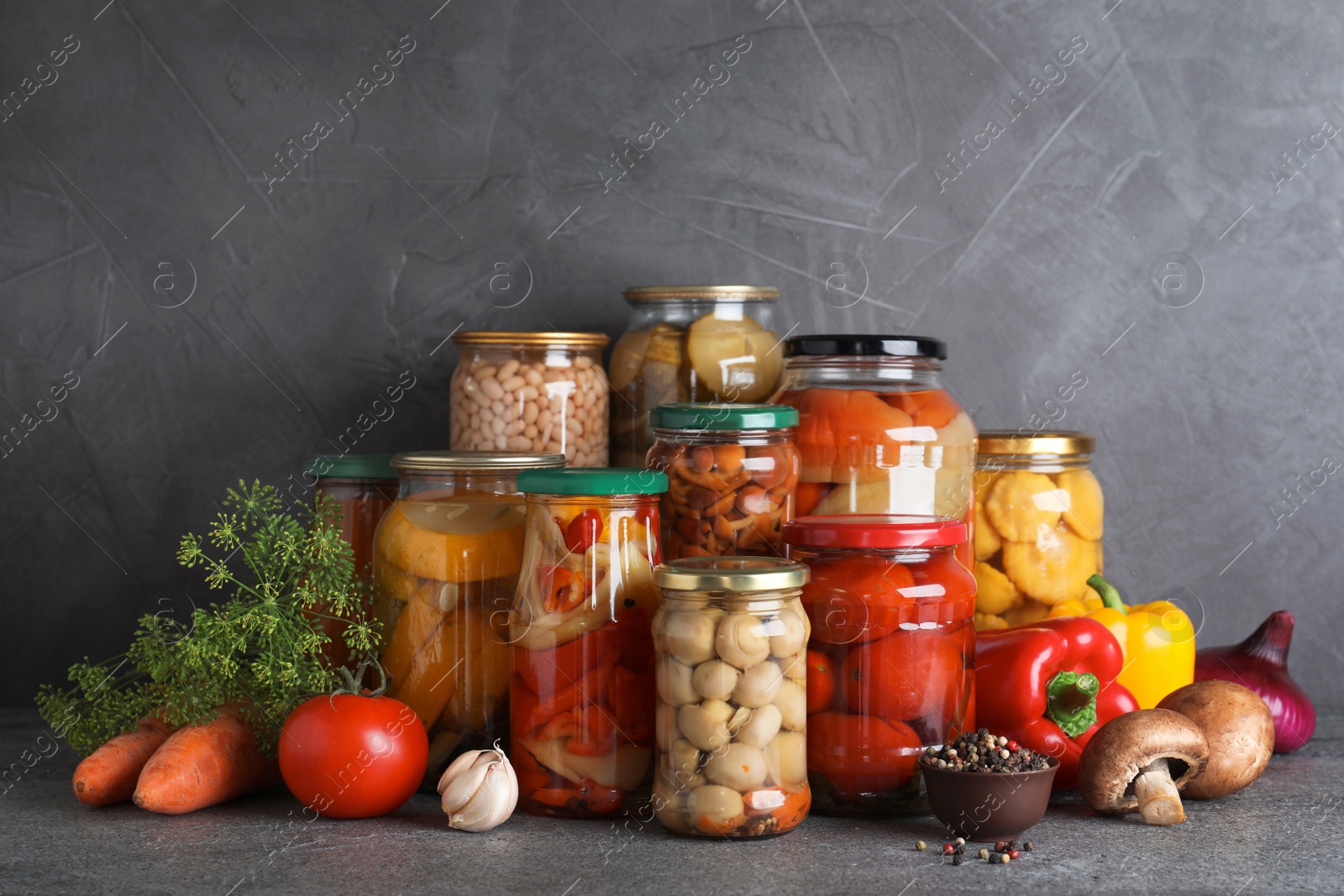 Photo of Jars of tasty pickled vegetables on grey table