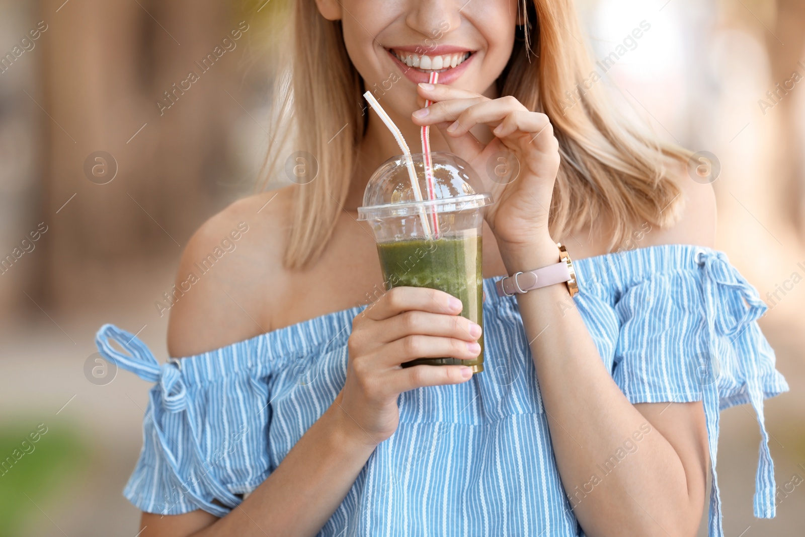 Photo of Young woman with plastic cup of healthy smoothie outdoors