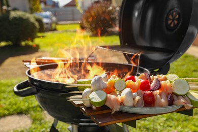Photo of Skewers with meat and vegetables near barbecue grill outdoors